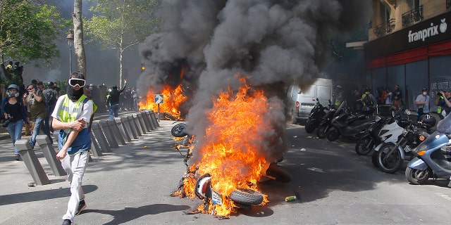 A man runs by a burning motorbike during a demonstration in Paris, Saturday. 