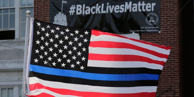 FILE - In this July 28, 2016, file photo, a flag with blue and black stripes in support of law enforcement officers, flies at a protest by police and their supporters outside Somerville City Hall in Somerville, Mass. (Associated Press)