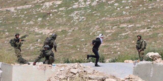 Osama Hajahjeh, 16, bound and blindfolded, runs away from the Israeli soldiers near the village of Tekoa in the West Bank. Hajahjeh said he was shot in the legs by Israeli soldiers last week when he was handcuffed and blindfolded shortly after his arrest. (AP Photo / Mohammad Hmeid)
