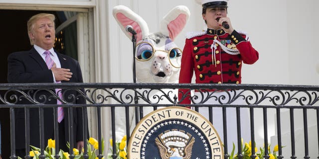 President Donald Trump, joined by the Easter Bunny, sings the national anthem with a member of the "The President's Own," United States Marine Band, from the Truman Balcony of the White House in Washington, Monday, April 22, 2019, during the annual White House Easter Egg Roll. (AP Photo/Alex Brandon)