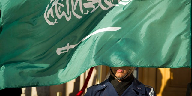 Honor Guard member is covered by the flag of Saudi Arabia 