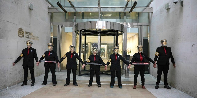 Extinction Rebellion climate protesters form a line after glueing themselves to the entrances of the London Stock Exchange in the City of London, Thursday April 25, 2019.