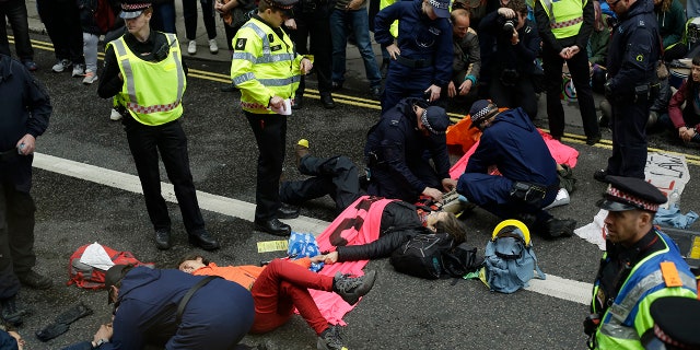 Extinction Rebellion climate change protesters are being removed from a road block by police, outside the Goldman Sachs International office in the City of London, Thursday, April 25, 2019. The non-violent protest group, Extinction Rebellion, is seeking negotiations with the government on its demand to make slowing climate change a top priority.