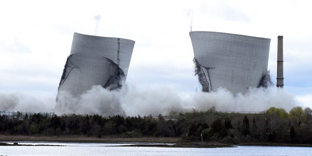 The two 500-foot cooling towers of the former Brayton Point Station collapse after explosive charges are detonated in Somerset, Mass.
