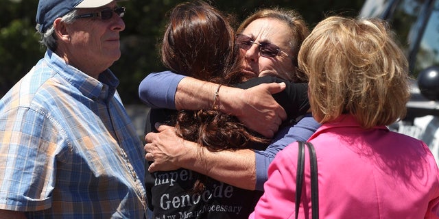 Members of the Chabad synagogue hug as they gather near the Altman Family Chabad Community Center, Saturday in Poway, Calif. (Associated Press)