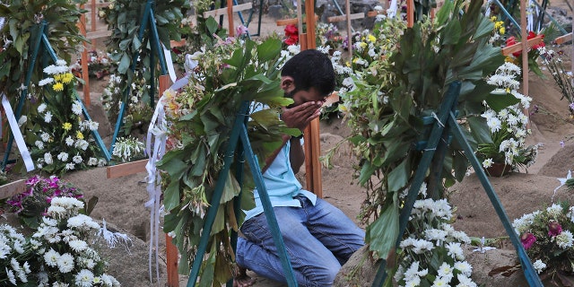 A Sri Lankan relative of a victim of Easter Sunday bomb blasts pays tribute at the burial site after a televised Sunday mass by Sri Lankan Archbishop Cardinal Malcolm Ranjith, in Negombo, north of Colombo, Sri Lanka. (AP Photo/Manish Swarup)
