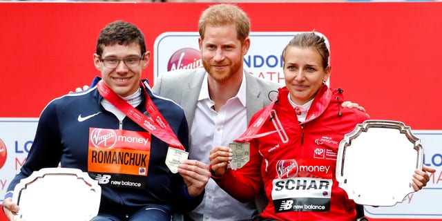 Britain's Prince Harry, center, poses with the men's wheelchair race first place winner Daniel Romanchuk of the United States, left, and women's wheelchair race first place winner Switzerland's Manuela Scharat, right, at the 39th London Marathon in London.