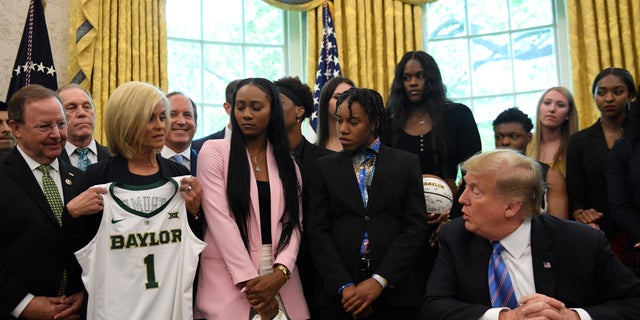 Women's basketball head coach Kim Mulkey, third from left, hands President Trump a jersey as he greets members of the Baylor women's basketball team, who are the national champions of NCAA 2019 Division 1 at the White House Oval Office on April 29, 2019. (AP Photo / Susan Walsh)