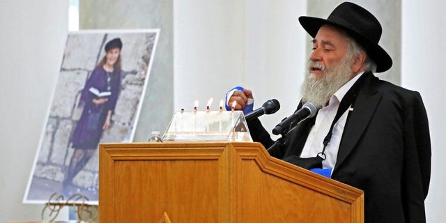 Yisroel Goldstein, Rabbi of Chabad of Poway, speaks Monday during the memorial service for Lori Kaye, who is pictured at left, in Poway, Calif.