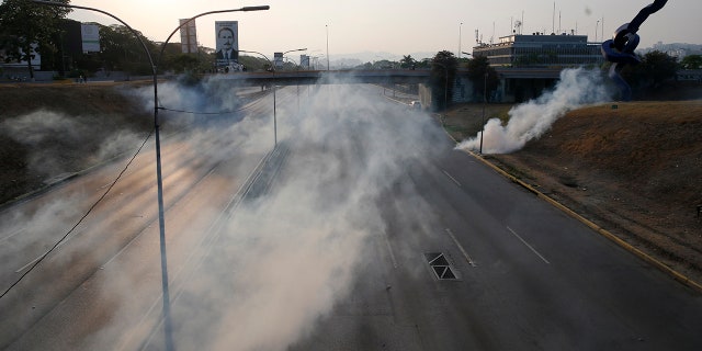 Tear gas covers an empty highway next to La Carlota air base in Caracas, Venezuela, Tuesday, April 30, 2019. Venezuelan opposition leader Juan Guaido appeared in a video with a small contingent of armed soldiers and formerly detained opposition activist Leopoldo Lopez calling for Venezuelans to take to the streets to oust President Nicolas Maduro. (AP Photo/Ariana Cubillos)