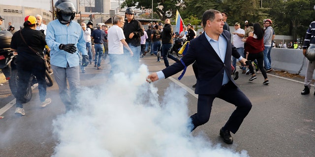 An opponent to Venezuela's President Nicolas Maduro returns a tear gas canister in Caracas, Venezuela, Monday, April 29, 2019. (AP Photo/Ariana Cubillos)