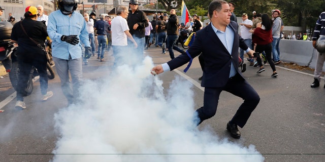 An opponent to Venezuela's President Nicolas Maduro returns a tear gas canister in Caracas, Venezuela, Monday, April 29, 2019. (AP Photo/Ariana Cubillos)