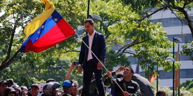 Venezuela's opposition leader and self-proclaimed President Juan Guaido stands above supporters as he addresses them outside La Carlota military air base in Caracas, Venezuela, Tuesday, April 30, 2019. Guaidó has taken to the streets with activist Leopoldo Lopez and a small contingent of heavily armed troops early Tuesday in a bold and risky call for the military to rise up and oust socialist leader Nicolas Maduro. (AP Photo/Fernando Llano)
