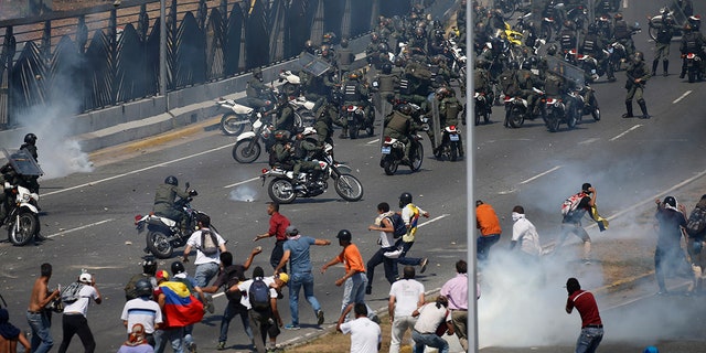 Opponents to Venezuela's President Nicolas Maduro confront loyalist Bolivarian National Guard troops firing tear gas at them, outside La Carlota military airbase in Caracas, Venezuela, Tuesday, April 30, 2019. (AP Photo/Fernando Llano)