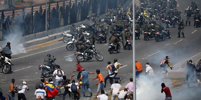 Opponents to Venezuela's President Nicolas Maduro confront loyalist Bolivarian National Guard troops firing tear gas at them, outside La Carlota military airbase in Caracas, Venezuela, Tuesday, April 30, 2019. (AP Photo/Fernando Llano)