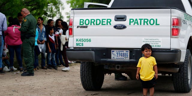 In this Thursday, March 14, 2019, photo, William Josue Gonzales Garcia, 2, who was traveling with his parents, with other families who crossed the nearby US-Mexico border near McAllen, Texas. They are waiting for Border Patrol agents to check names and documents. Immigration authorities say they expect the ongoing surge of Central American families to cross the border to multiply in the coming months. (AP Photo / Eric Gay)
