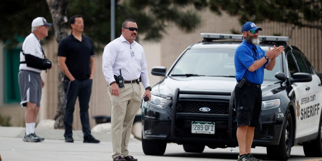 School police officers look on as students leave Columbine High School late Tuesday, April 16, 2019, in Littleton, Colo.