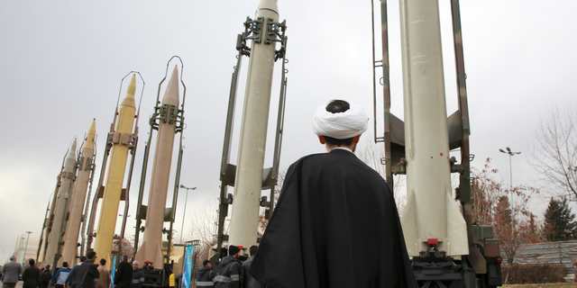 FILE - In this Feb. 3, 2019 file photo, an Iranian clergyman looks at domestically built surface to surface missiles displayed by the Revolutionary Guard in a military show marking the 40th anniversary of the Islamic Revolution, at Imam Khomeini Grand Mosque in Tehran, Iran. On Monday, April 8, 2019, the Trump administration designated Iran’s Revolutionary Guard a “foreign terrorist organization” in an unprecedented move against a national armed force. Iran’s Revolutionary Guard Corps went from being a domestic security force with origins in the 1979 Islamic Revolution to a transnational fighting force. (AP Photo/Vahid Salemi, File)