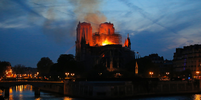 Firefighters tackle the blaze as flames and smoke rises from Notre Dame cathedral as it burns in Paris, Monday, April 15, 2019. Massive plumes of yellow-brown smoke are filling the air above Notre Dame Cathedral and ash is falling on tourists and others around the island that marks the center of Paris. (AP Photo/Michel Euler)