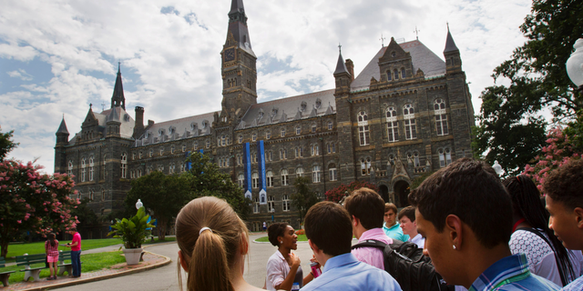 FILE - In this July 10, 2013, file photo, prospective students tour Georgetown University's campus in Washington. Georgetown University students are considering a fee benefiting the descendants of enslaved people sold to pay off the school’s debts, an effort that would create one of the first reparations funds at a major U.S. institution. Undergraduates will vote Thursday, April 11, 2019 on a $27.20-per-semester fee that would go toward underprivileged communities where some descendants live. (AP Photo/Jacquelyn Martin, File)