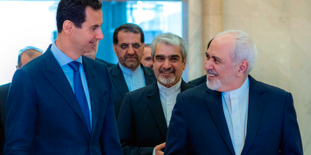 This photo released on the official Facebook page of Syrian Presidency shows Syrian President Bashar Assad, left, speaking with Iranian Foreign Minister Mohammad Javad Zarif, right, in Damascus, Syria, Tuesday, April 16, 2019. (Syrian Presidency Facebook page via AP)