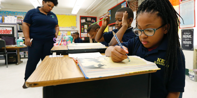 Elize'a Scott, a Key Elementary School third grade student reads under the watchful eyes of teacher Crystal McKinnis. (AP Photo/Rogelio V. Solis)