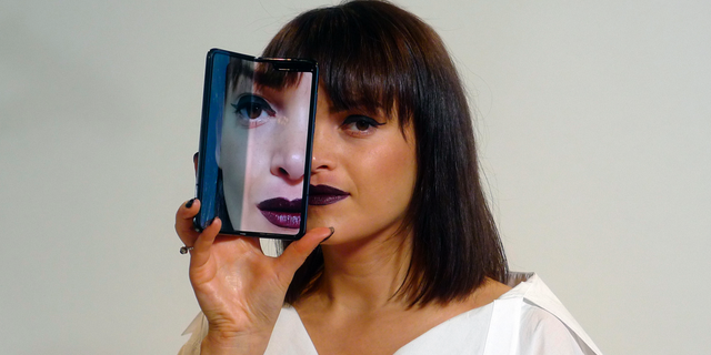 A model holds a Samsung Galaxy Fold smartphone to her face, during a media preview event in London. (AP Photo/Kelvin Chan)