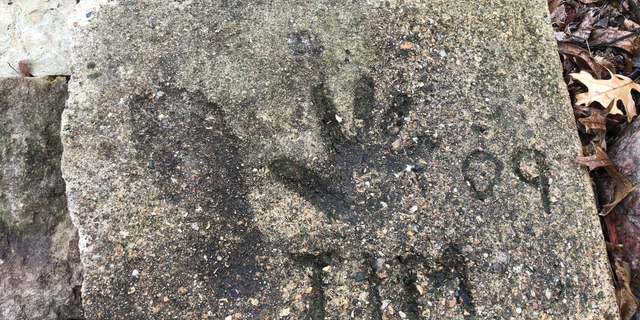 A slab of concrete sits in the backyard of the house where Timmothy Pitzen used to live in Aurora, Ill., Thursday, April, 4, 2019. The man who lives in the house now, Pedro Melendez, says he didn't know the boy but saved the concrete slab with Tim's name, handprint and footprint etched in it when he redid the back patio. Authorities conducted DNA testing to try to determine Thursday whether a teenager found wandering the streets of a Kentucky town is who he claims to be — an Illinois boy who disappeared eight years ago around the time his mother took her own life. (AP Photo/Carrie Antlfinger)