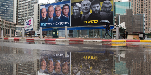 FILE - In this Saturday, March 16, 2019 file photo, an Ultra-Orthodox Jewish man looks at an elections billboards of the Blue and White party leaders, from left to right, Moshe Yaalon, Benny Gantz, Yair Lapid and Gabi Ashkenazi, alongside a panel on the right showing Prime Minister Benjamin Netanyahu flanked by extreme right politicians, from the left, Itamar Ben Gvir, Bezalel Smotrich and Michael Ben Ari in Ramat Gan, Israel, In a charged campaign that has been heavy on insults and short on substance, Israel's conflict with the Palestinians has been notably absent from the discourse. Hebrew reads on the left billboard "The nation of Israel lives" and on the right billboard "Kahana Lives" in a reference to a banned ultranationalist party. (AP Photo/Oded Balilty, File)