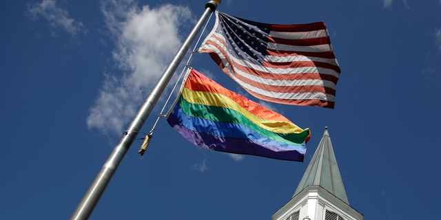 A gay pride rainbow flag flies along with the U.S. flag in front of the Asbury United Methodist Church in Prairie Village, Kan., on Friday, April 19, 2019. There's at least one area of agreement among conservative, centrist and liberal leaders in the United Methodist Church: America's largest mainline Protestant denomination is on a path toward likely breakup over differences on same-sex marriage and ordination of LGBT pastors. (AP Photo/Charlie Riedel)