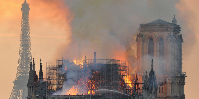 In this image made available on Tuesday April 16, 2019 flames and smoke rise from the blaze after the spire toppled over on Notre Dame cathedral in Paris, Monday, April 15, 2019.