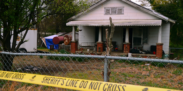In this Friday, April 5, 2019, photo, police tape marks the area where the Spartanburg County Sheriff's Office and Spartanburg County Coroner's were working after two bodies were found buried on the property on Williams Street in Spartanburg, S.C. Two men have been charged with murder in connection with the discovery. (Tim Kimzey/Spartanburg Herald-Journal via AP)