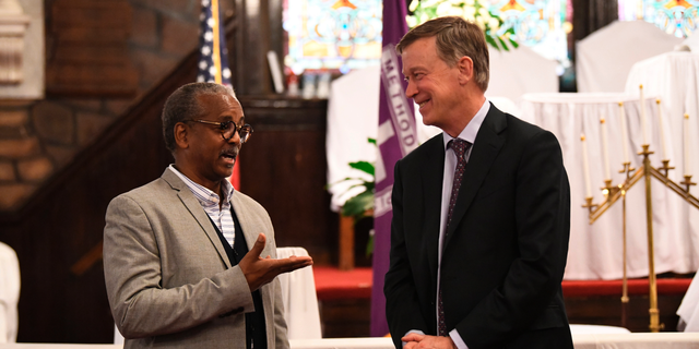 Former Colorado Gov. John Hickenlooper discusses gun control and death penalty issues with Anthony Thompson on Saturday, April 6, 2019, in Charleston, S.C. Thompson's wife was slain in a massacre that claimed nine Bible study participants at a historic black church in South Carolina. Hickenlooper, a staunch advocate for gun control legislation, visited Mother Emanuel during a campaign trip to the state as he seems the Democratic presidential nomination. (AP Photo/Meg Kinnard)