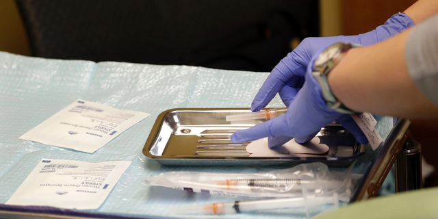 A healthcare worker prepares syringes containing measles, mumps, and rubella (MMR) vaccines for child immunizations at the International Community Health Service in Seattle. Officials in the Pacific Northwest say the measles epidemic that has sickened multiple people is over.