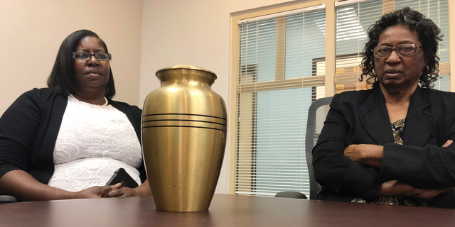 Corene Nero, right, and her daughter Gloria Rolle speak at their attorneys office next to an urn with cremated remains, in Boca Raton, Fla., Tuesday, April 16, 2019. Robert Nero Sr., passed away in 2013 and was cremated by Taylor Smith funeral home. In March, West Palm Beach police Department found a box with Robert Nero's name on it filled with ashes. Now the family is demanding answers from the funeral home and want to return the remains they have to the right family. (AP Photo/Josh Repogle)