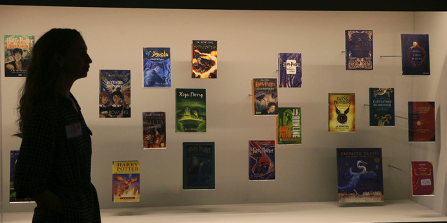 FILE - In this Wednesday Oct. 18, 2017 file photo, a member of British Library staff poses for a picture with Harry Potter books published in several languages at the "Harry Potter - A History of Magic" exhibition at the British Library, in London. Priests at a Catholic parish in northern Poland have burned books, including the “Harry Potter” series, and other items that their owners said had evil forces. Images from the burning at Gdansk’s Mother of Church parish on Sunday March 31, 2019, were posted on Facebook by a Catholic foundation that uses unconventional ways of religious work. (AP Photo/Tim Ireland, File)