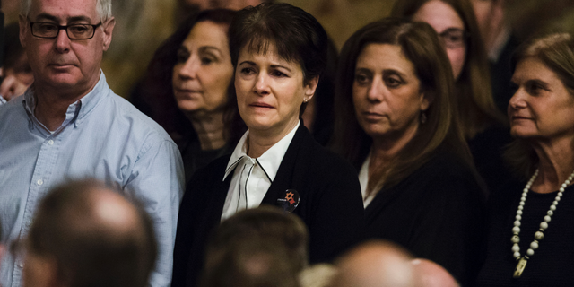 Andrea Wedner, center, who was wounded at the Pittsburgh synagogue attack that killed 11 people last year, stands with others as they are acknowledged by Pennsylvania lawmakers who came together in an unusual joint session to commemorate the victims of synagogue attack, Wednesday, April 10, 2019, at the state Capitol in Harrisburg, Pa. (AP Photo/Matt Rourke)