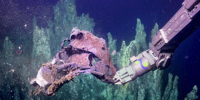 ROV SuBastian picks up some discarded trash near Big Pagoda vent in the Guaymas Basin. (Courtesy of Schmidt Ocean Institute)
