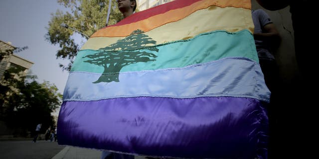 A gay pride flag bearing the cedar tree in the middle of it is carried by human rights activists during an anti-homophobia rally in Beirut on April 30, 2013. Top Lebanese military prosecutors acquitted four military personnel Saturday in a landmark ruling that affirms homosexuality is not a crime.