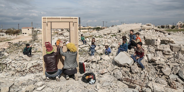 Puppeteer Walid Rashed performs a puppet act for Syrian children, in the midst of the rubble of damaged buildings, to mark the World Theatre Day as part of his tour of Saraqib in the rebel-held province of Idlib. 