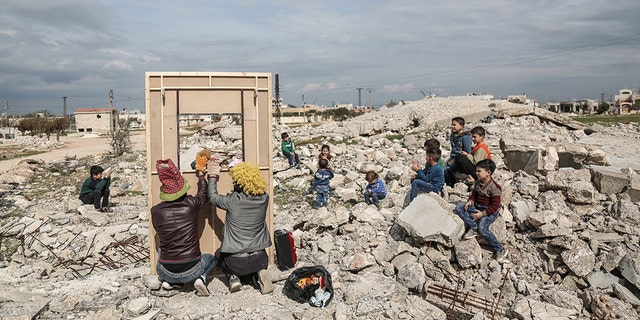 Puppeteer Walid Rashed performs a puppet act for Syrian children, in the midst of the rubble of damaged buildings, to mark the World Theatre Day as part of his tour of Saraqib in the rebel-held province of Idlib.