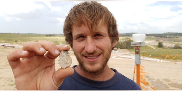 IAA Archaeologist Avinoam Lehavi holding the ancient oil lamp sherd decorated with a menorah. (Anat Rasiuk, Israel Antiquities Authority)