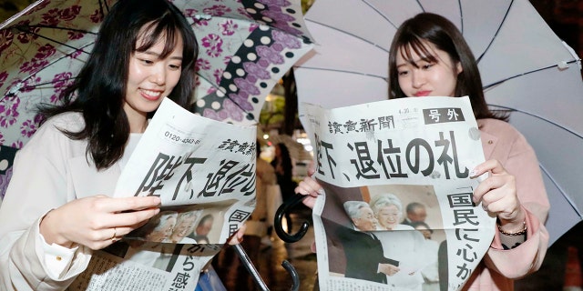 Women read a copy of the extra edition of Yomiuri Shimbun newspaper reporting Emperor Akihito's abdication in Tokyo Tuesday. The headline reads "Emperor, abdication ritual." (Kyodo News via AP)