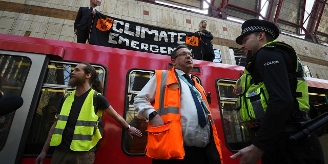 Police and officials stand as climate activists lighthouse protests on a Dockland Light railroad car at Canary Wharf station in London as part of ongoing climate change demonstrations in the capital, Wednesday, April 17, 2019. Environmental protest group Extinction Rebellion calls for public protests With civil disobedience over several days to highlight what it says is the lack of addressing the causes of climate change.