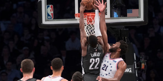 Brooklyn Nets guard Caris LeVert (22) dunks past Philadelphia 76ers center Joel Embiid (21) during the first half of Game 4 of a first-round NBA basketball playoff series, Saturday, April 20, 2019, in New York. (AP Photo/Mary Altaffer)