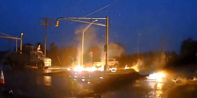 Flames can be seen following the fall of an electric line on the soggy ground and its bursting into a fireball as a utility worker was near New Jersey on Monday.