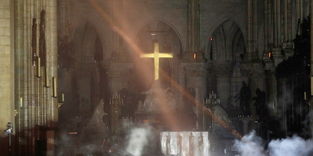 Smoke is seen around the alter inside Notre Dame cathedral in Paris, Monday, April 15, 2019. The golden altar cross could be seen glowing as firefighters made their way in.