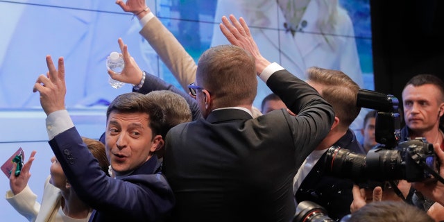 In this Sunday, April 21, 2019, photo, Ukrainian comedian and presidential candidate Volodymyr Zelenskiy, left, makes the victory sign after seeing the exit polls for the second round of presidential elections in Kiev, Ukraine.