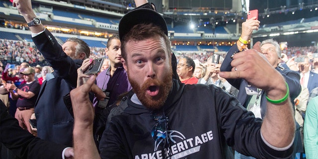 A man gestures towards the press corps after throwing an object on stage towards US President Donald Trump as he is speaking at the National Rifle Association (NRA) Annual Meeting at Lucas Oil Stadium in Indianapolis, Indiana, April 26, 2019. - The man was later removed from the scene by Secret service agents. (Photo by SAUL LOEB / AFP) (Photo credit should read SAUL LOEB/AFP/Getty Images)