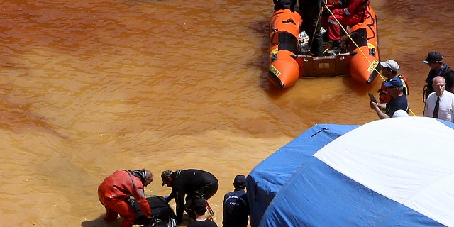 A diver, left, and an Investigator hold a suitcase found in a man-made lake, near the village of Mitsero outside of the capital Nicosia, Cyprus, Sunday, April 28, 2019.